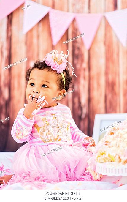 Mixed Race baby eating birthday cake