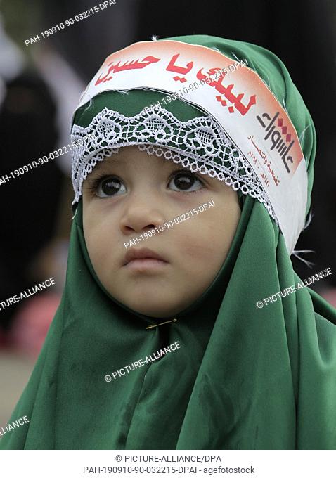 10 September 2019, Yemen, Sanaa: A Yemeni girl wearing a bandana with with an Arabic inscription reading, ""On your Service Hussein""