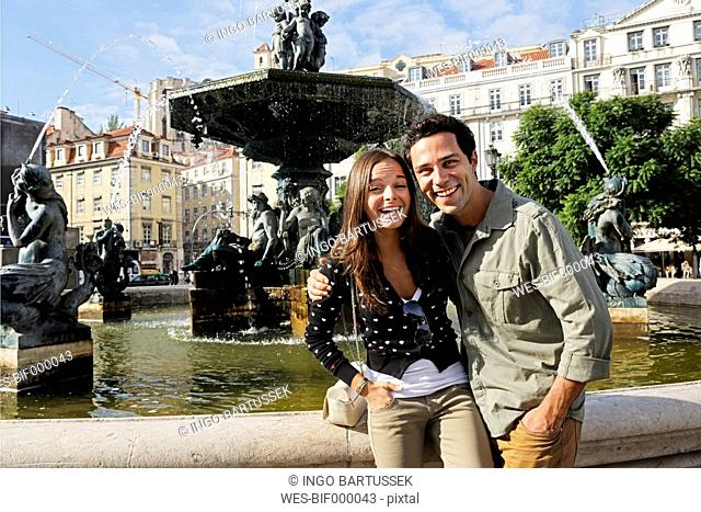 Portugal, Lisboa, Baixa, Rossio, Praca Dom Pedro IV, smiling young couple in front of a fountain
