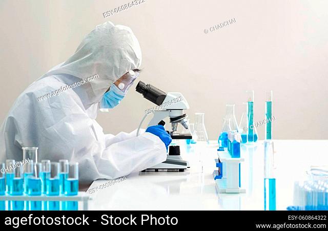 Epidemiological researcher in virus protective clothing use microscopes to look at blood samples of infected people. Coronavirus disease 2019