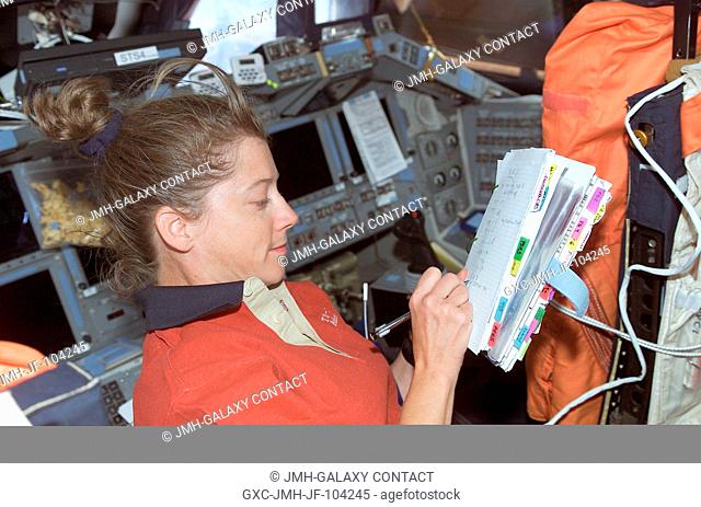 Astronaut Pamela A. Melroy, STS-112 pilot, looks over a procedures checklist on the flight deck of the Space Shuttle Atlantis