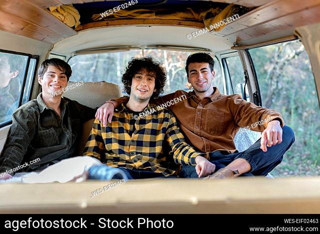 Young friends sitting in campervan on weekend