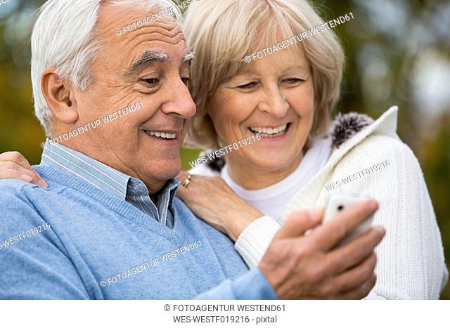 Portrait of smiling senior couple looking self-portrait at smartphone