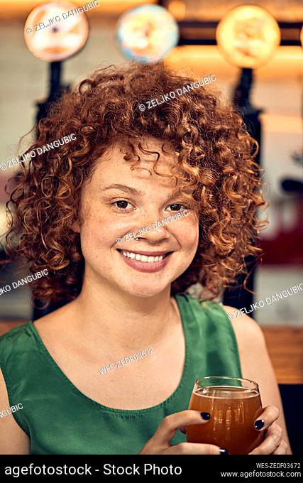 Portrait of a smiling woman in a pub having a beer