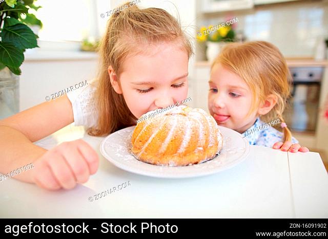Zwei Kinder kosten von einem frischen Napfkuchen in der Küche