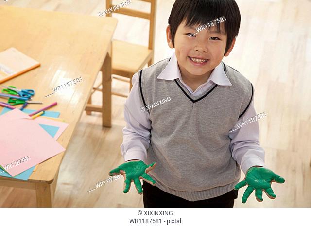 Portrait of smiling schoolboy finger painting in art class, Beijing