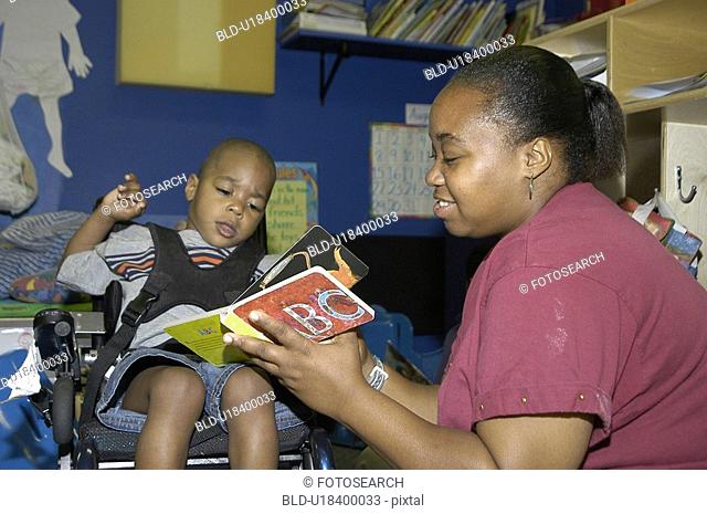 Student with a disability receiving assistance from his teacher to read a book