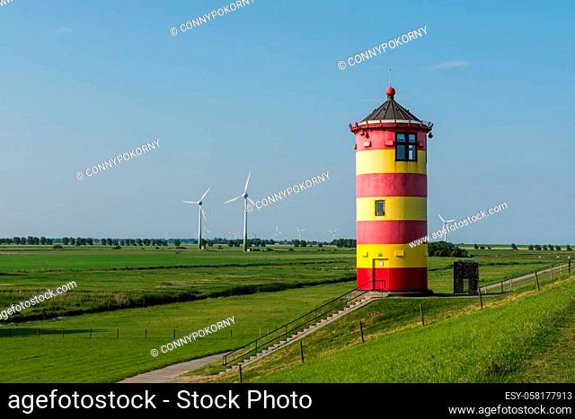 Pilsum Lighthouse on a dike with wind turbines in background. The Pilsum Lighthouse was built in 1891 and is located near the East Frisian village of Greetsiel...