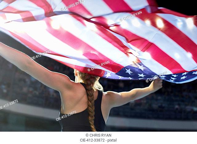 Female athlete running victory lap with American flag