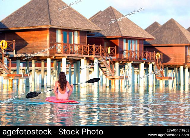 Beautiful woman surfing on stand up paddle board at exotic vacation