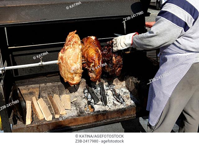 Man cooking Prague ham and other meat on a rotisserie in Old Town Square, Prague, Czech Republic, historical center listed as World Heritage by UNESCO