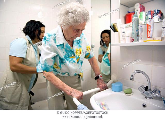 Rotterdam, Netherlands. A professional nurse of a Rotterdam nursing home helping an elderly inhabitant getting dressed inside her nursing home bathroom