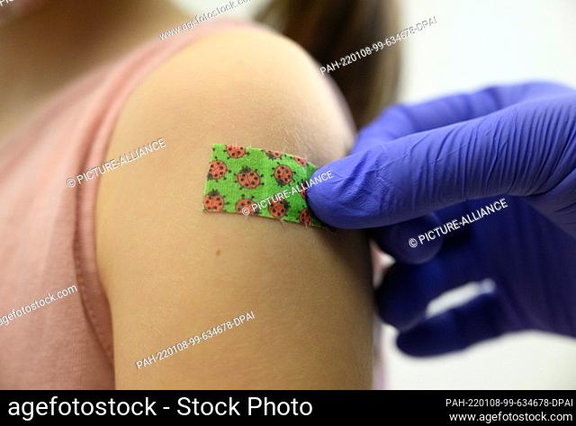 08 January 2022, Saxony, Dresden: A seven-year-old girl gets a plaster stuck on her arm after being vaccinated against the coronavirus during a vaccination...