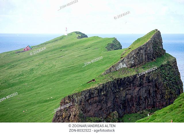 Mykines-Holmur auf den Färöer Inseln mit Leuchtturm, grünem Gras und Klippen / Mykines-Holmur on the Faroe Islands, with green grass, cliffs, and rocks