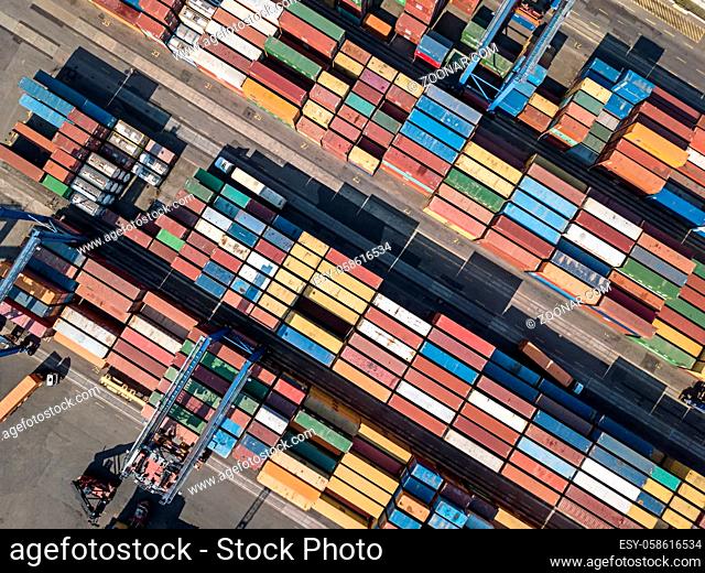 Top view at the warehouse with many multicolored containers. There are cranes and trucks. Horizontal photo. Outdoors