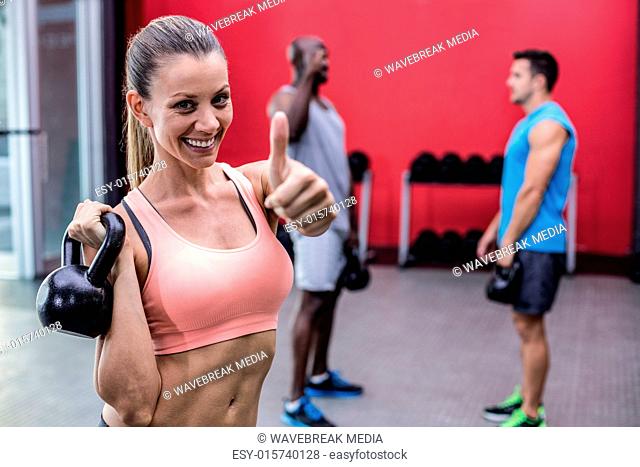 Smiling muscular woman lifting a kettle bell
