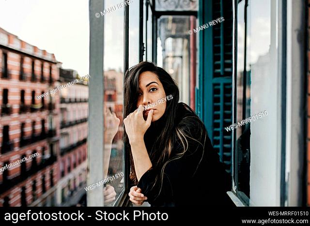Lonely young woman leaning on glass window
