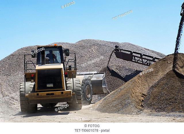 Bucket loader moving pile of gravel