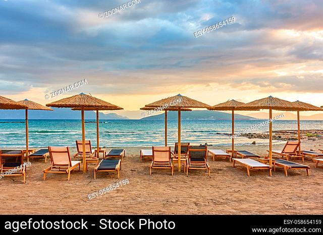 Sea beach with rows of straw parasols at sunset, Aegina Island, Greece - Greek landscape
