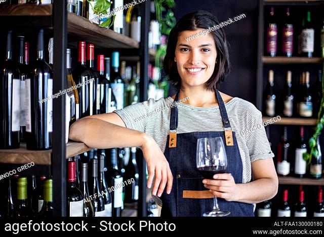 Female sommelier holding glass of wine while looking at the camera