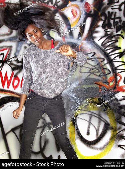 Black woman dancing near graffitied wall