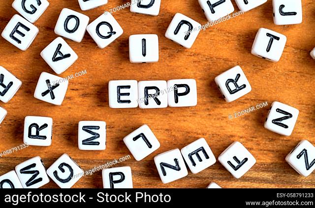 Small white and black bead cubes on wooden board, letters in middle spell ERP - Enterprise resource planning concept