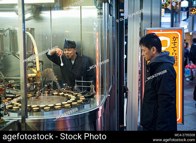 Kyoto, Japan, Asia - A man stands in front of a shop window of a confectionery - patisserie and watches the production of pastries