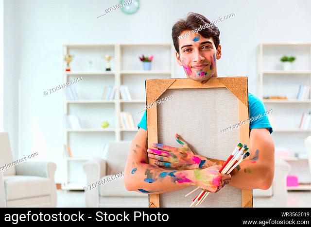 Young funny artist working on new painting in his studio