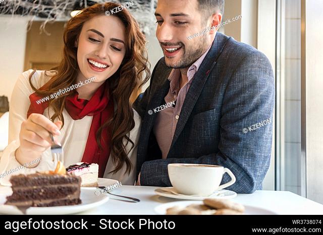 Delicious layered cake served with coffee on the table of a young couple in love during romantic date in a trendy cafeteria