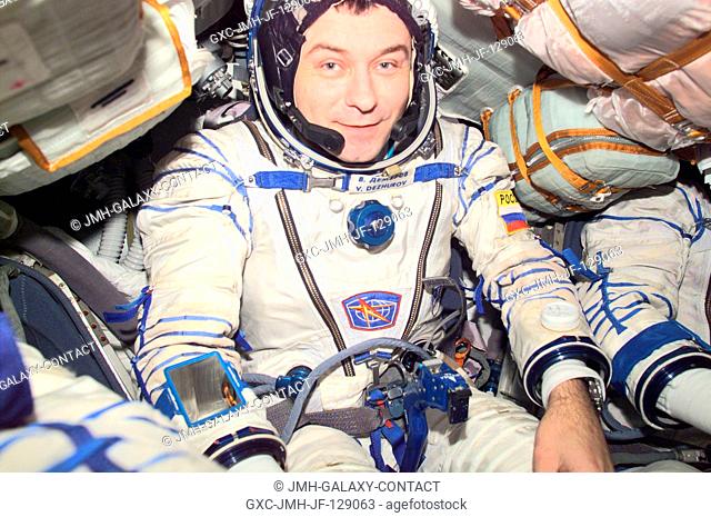 Cosmonaut Vladimir N. Dezhurov, Expedition Three flight engineer, wearing a Russian Sokol suit, is seated in the Soyuz spacecraft that is docked to the...