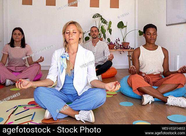 Blond businesswoman practicing yoga with colleagues in office