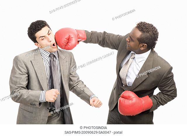 Businessman punching his co-worker with boxing gloves