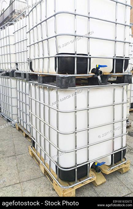 Lots of cube water tanks. 1000 litres containers piled outdoors