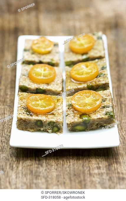 Six pistachio & almond squares with kumquats on a platter