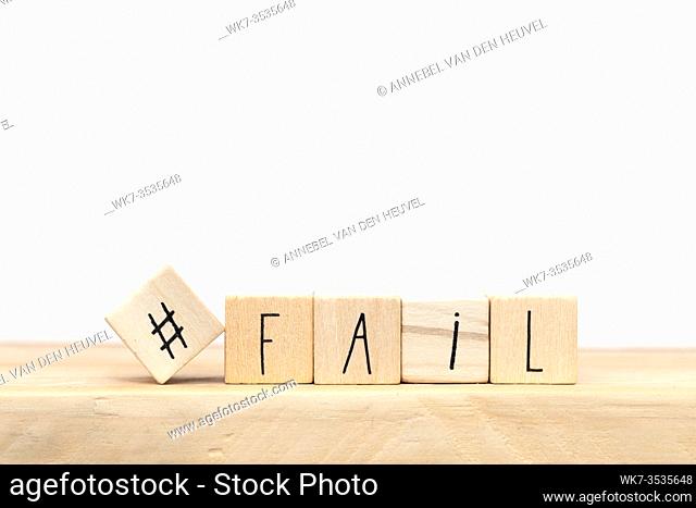 wooden cubes with a hashtag and the word fail near white background, social media design close-up