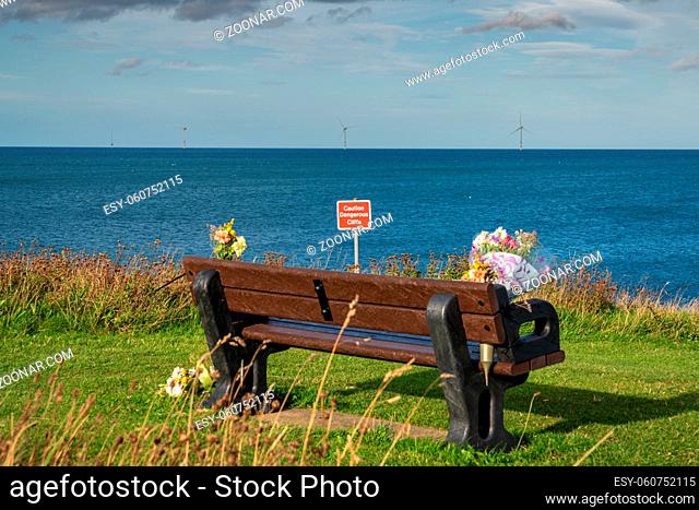 A bench with flowers, seen at North Sea coast in Collywell Bay, Seaton Sluice in Northumberland, England, UK
