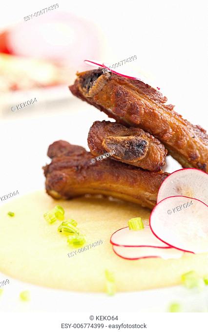 traditional Italian roasted pork ribbs served on polenta bed, corn cream
