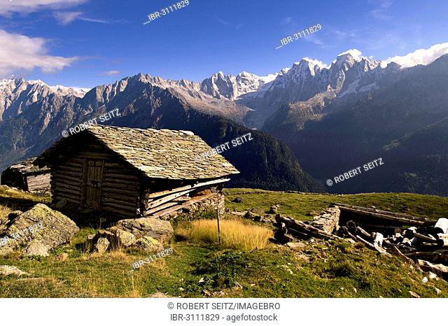 Old wooden hut with slated roof, peaks of the Bregaglia Range at back