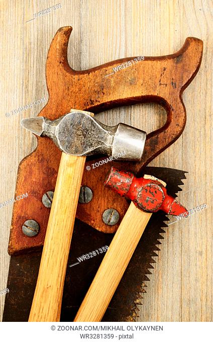 two hammer and old saw on wooden background
