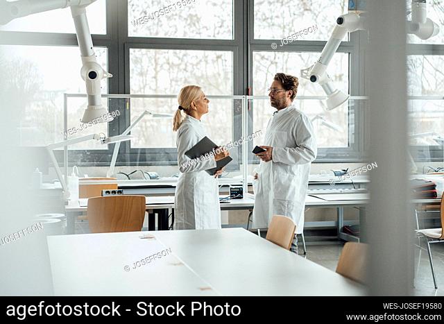 Mature scientist having discussion with colleague in laboratory