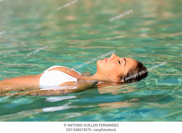 Side view portrait of a relaxed woman floating in a tropical beach water