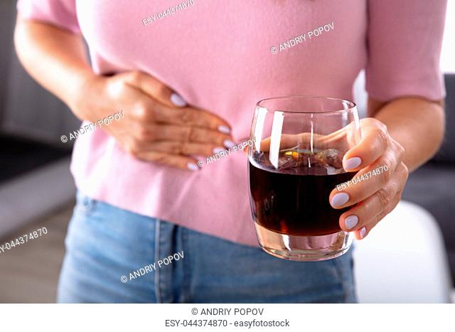Midsection View Of A Woman Suffering From Stomach Pain Holding Glass Of Drink