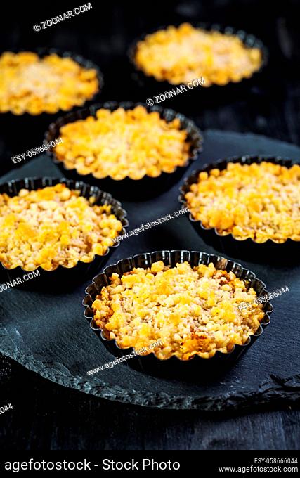 Small and delicious apple pies or apple crumble on black background. Apple tart