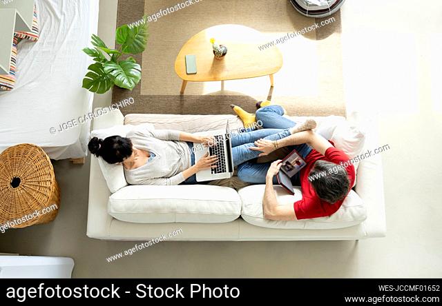 Couple relaxing on sofa in living room at home
