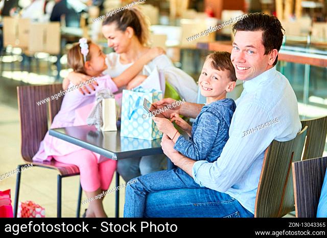 Glückliche Familie macht eine Pause beim Shopping im Einkaufszentrum