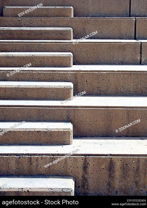 Modern outdoor concrete ascending steps with raised area for seating in contrasting sunlight and shadow