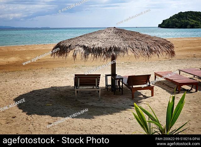 27 October 2019, Thailand, Ko Mak: Empty wooden loungers and umbrellas with thatched roofs are standing on the beach. The island is about 16 square kilometers...