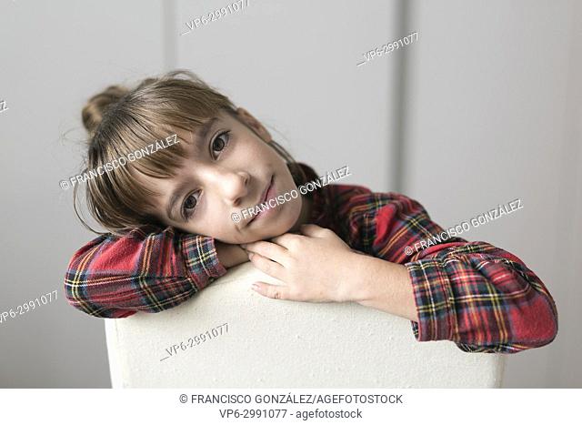 Portrait of a 10 year old girl sitting on a chair. Horizontal shot