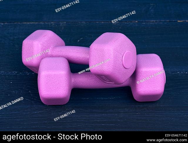 pink plastic dumbbells of one kilogram on a blue background, sports equipment