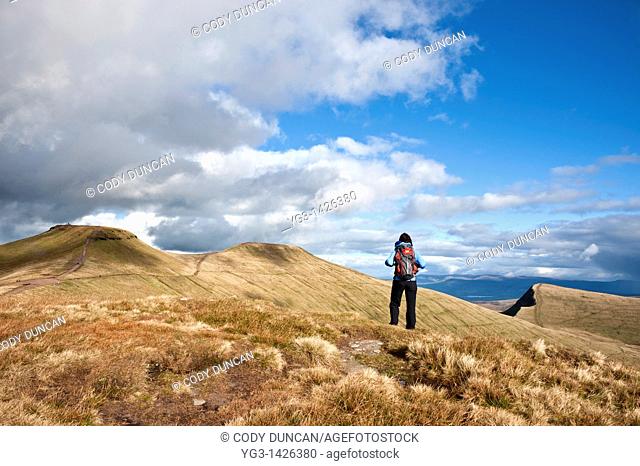 Female hiker hiking in mountains of Brecon Beacons national park with view of Pen Y Fan and Corn Du, Wales